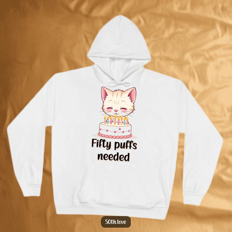 Funny 50th birthday hoodie depicting a smiling kitten struggling humorously to blow out fifty tiny candles on a small cake.